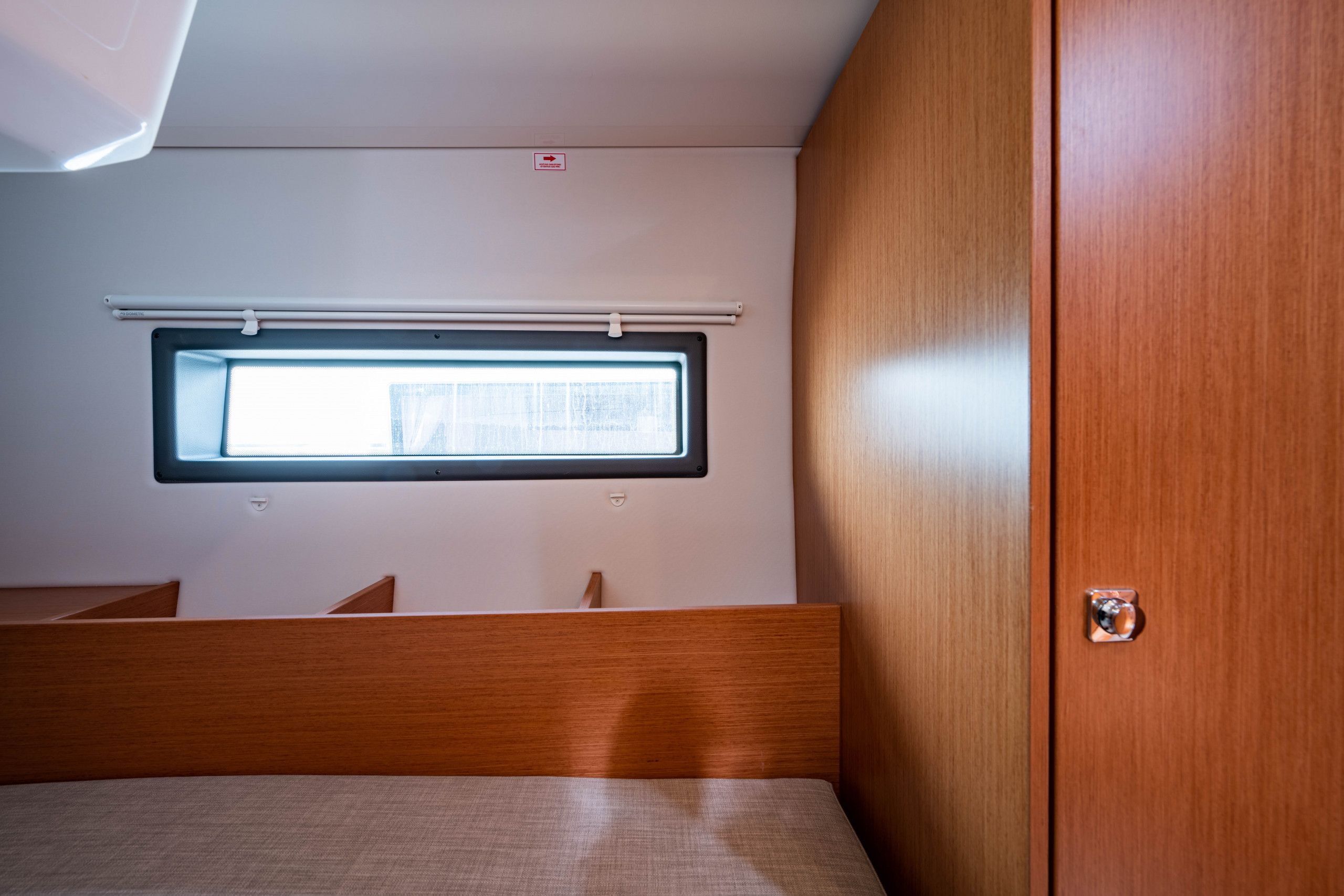 A compact room with a bed, a window, and a wooden wardrobe.