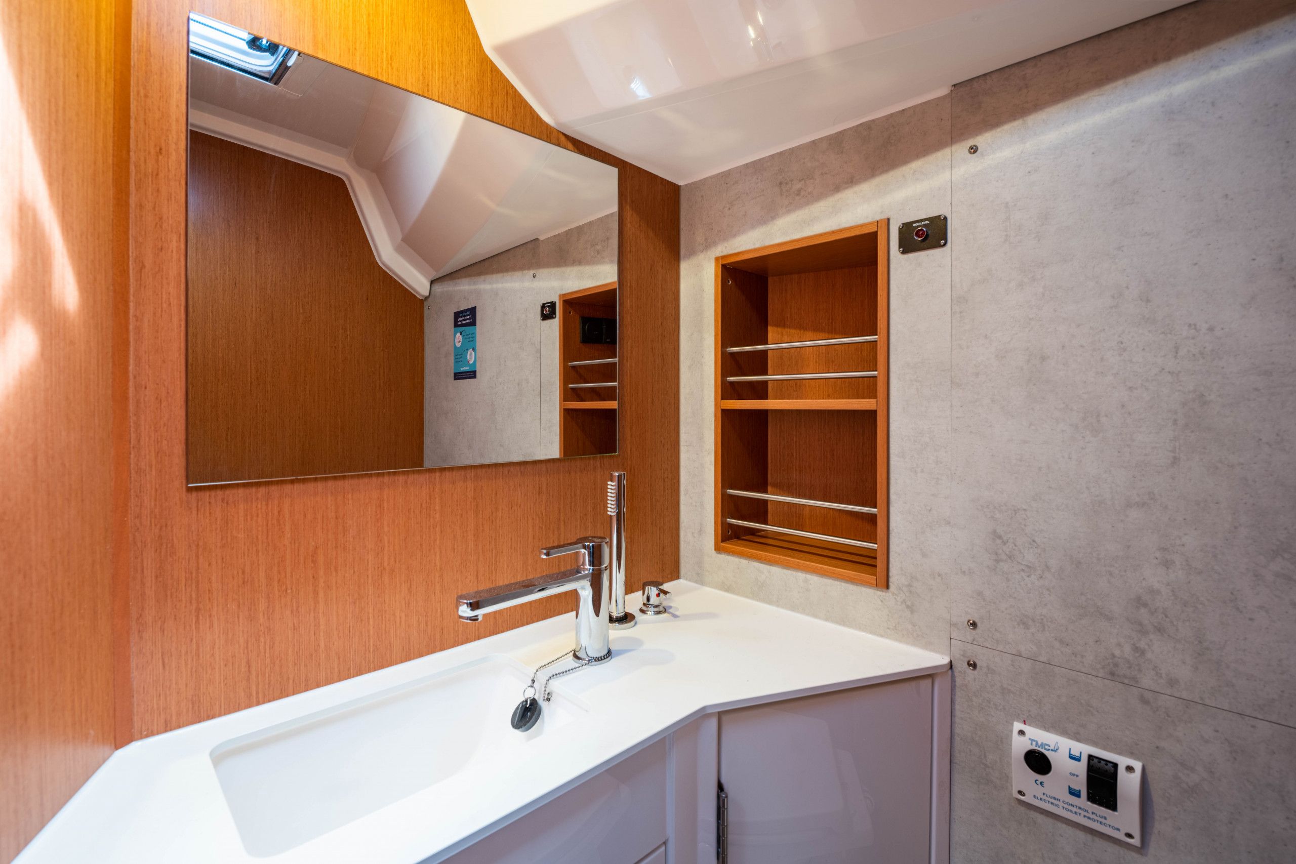 Une salle de bain moderne avec un lavabo blanc, un robinet chromé, des étagères en bois et un miroir.