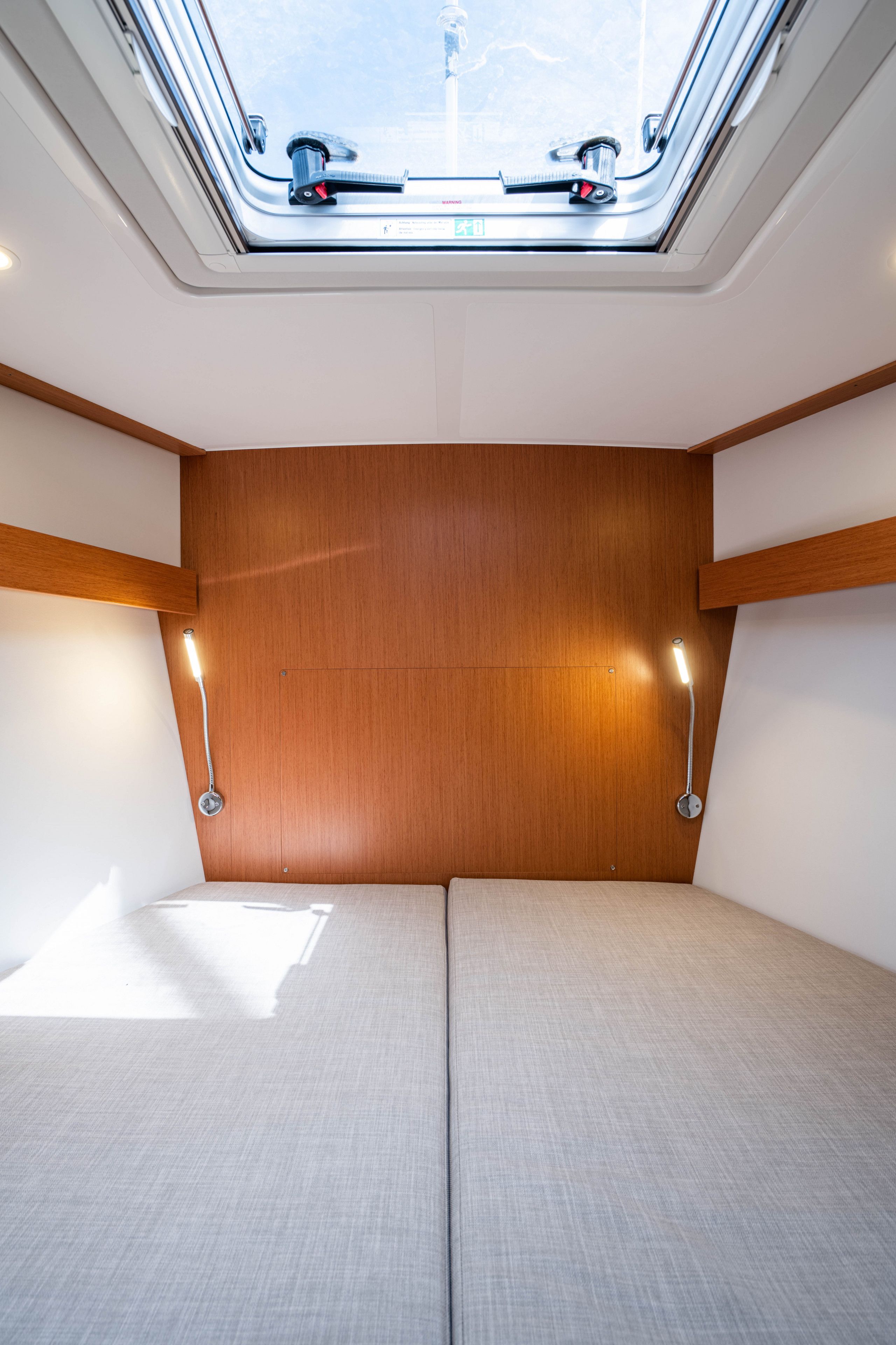 A compact room with a skylight, two bedside tables, and a bed.