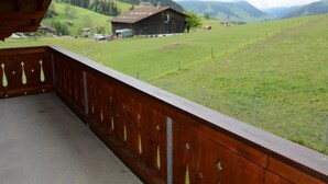 A balcony with a view of a rural landscape, including a barn and rolling hills. - Anne (2. Stock) Appartement/Fewo, Dusche oder Bad, WC 12-Bettwohnung by Interhome (Gstaad)
