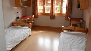 Une chambre avec deux lits en bois, un bureau et une chaise.