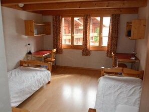 A room with two wooden beds, a desk, and a chair. - Anne (2. Stock) Appartement/Fewo, Dusche oder Bad, WC 12-Bettwohnung by Interhome (Gstaad)