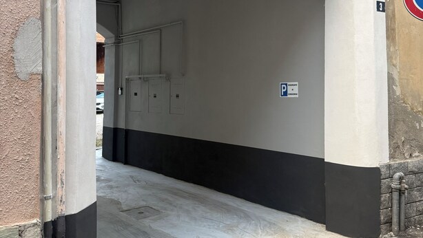 Un área de estacionamiento techada con pared blanca y negra, un letrero de 'No Estacionar' y un letrero de 'Reservado'.