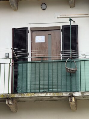 Un balcó amb una tanca de malla verda, una cistella de vimet i una porta amb el senyalitzador 'Smart Home'.