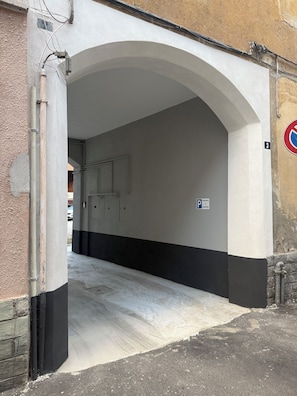 A covered parking area with a white and black wall, a 'No Parking' sign, and a 'Reserved' sign. - Gorla Minore Smart Home - Self-check-in near Malpensa (Gorla Minore)