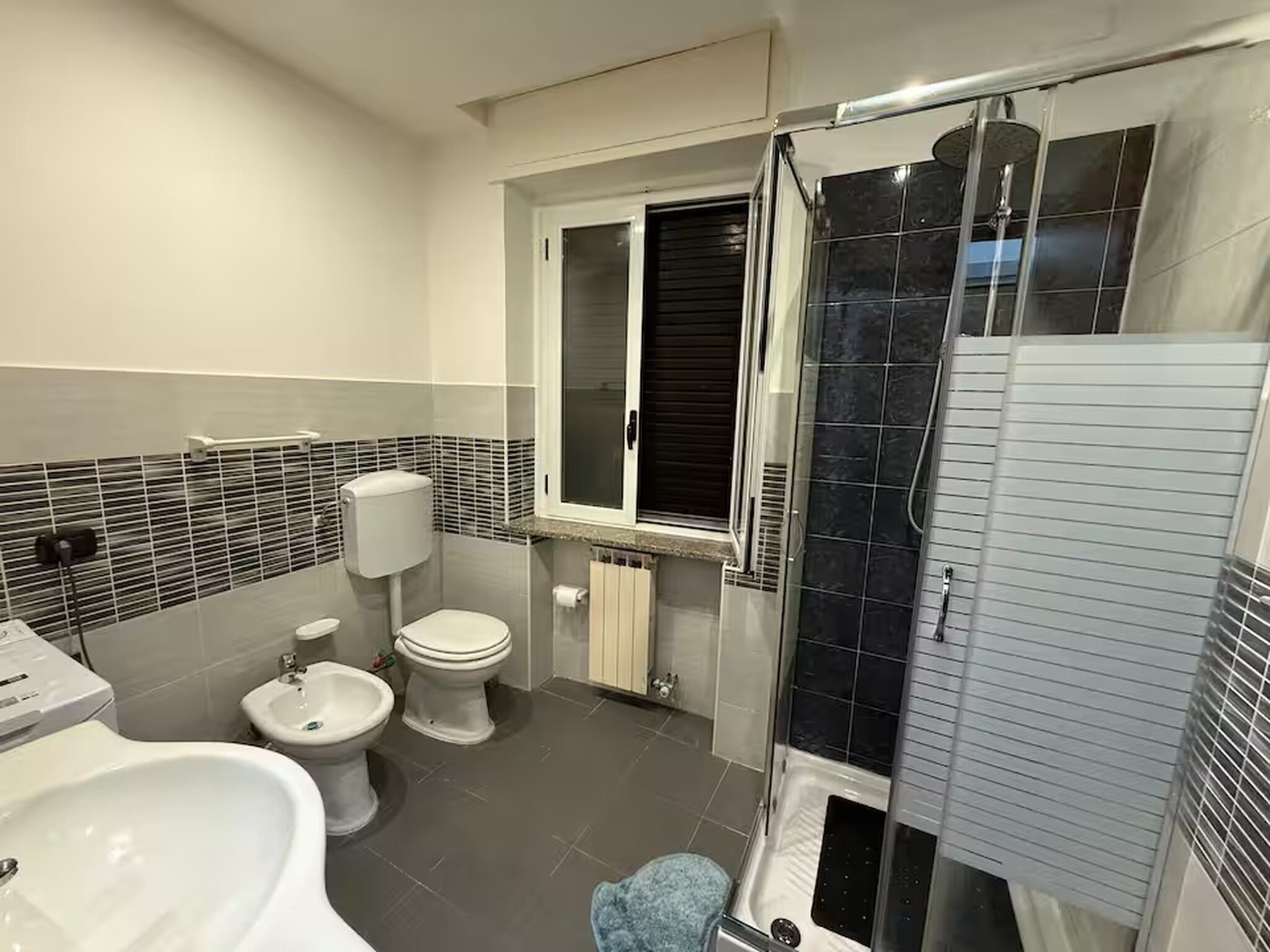 Une salle de bain moderne équipée de toilettes, d’un bidet et d’une douche à parois de verre.