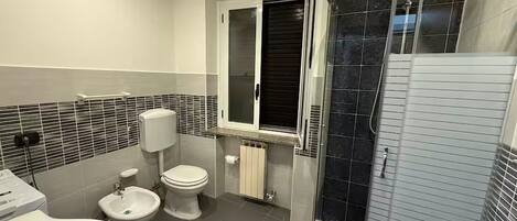 Une salle de bain moderne équipée de toilettes, d’un bidet et d’une douche à parois de verre.