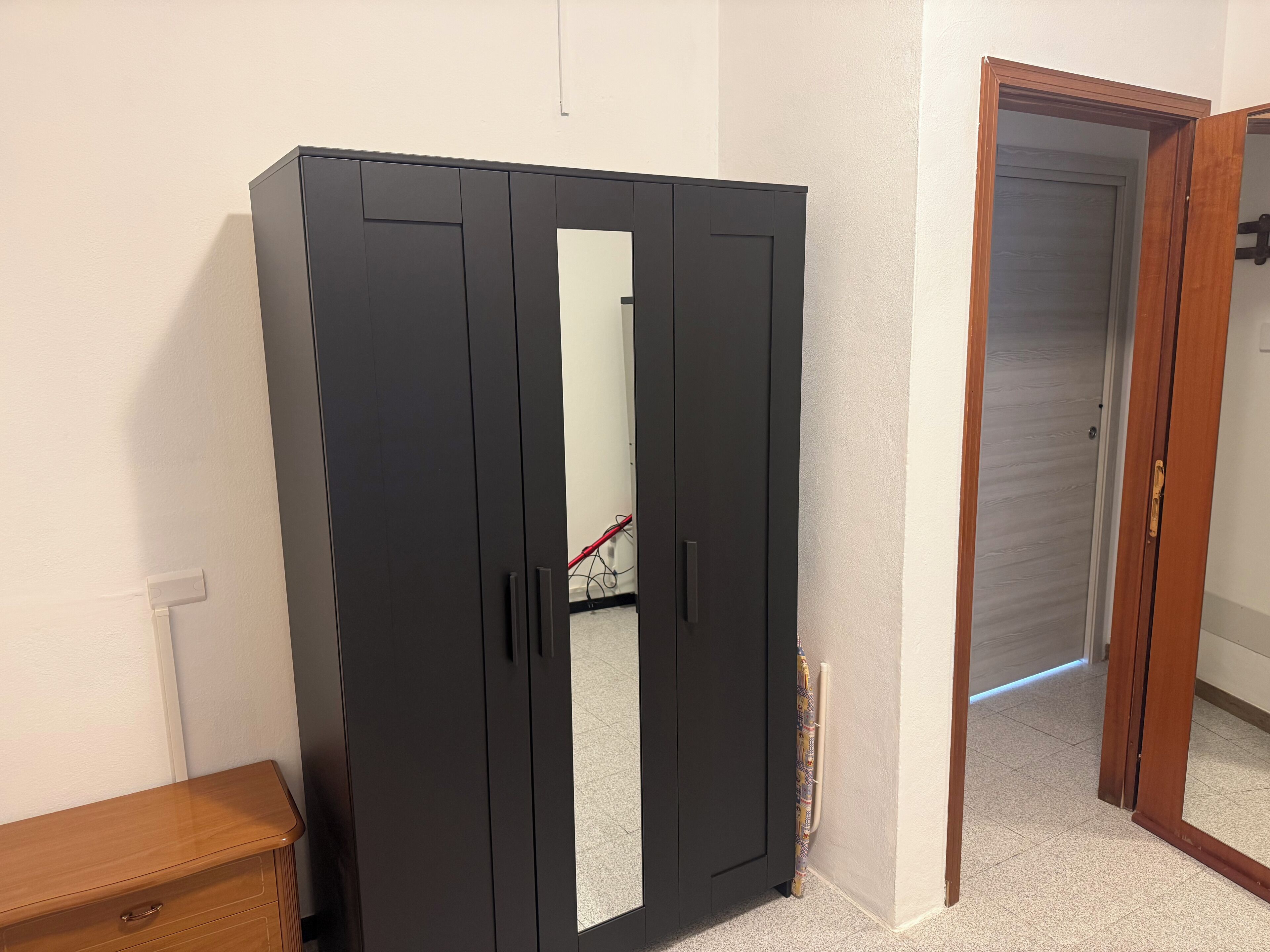 Une pièce dotée d’une grande armoire, d’un banc en bois et d’une porte donnant sur une autre pièce.