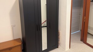 Una habitación con un armario grande, un banco de madera y una puerta que da a otra estancia.