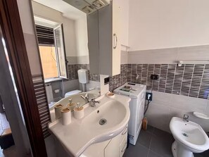 Een badkamer met een witte wastafel, een spiegel, een toilet en een bidet.