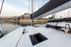 A sailboat docked at a marina with a view of a cityscape in the background.