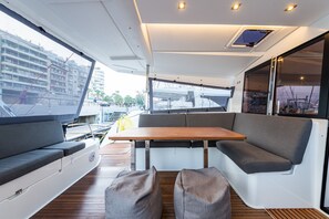 Schickes Yacht-Interieur mit Holztisch, gepolsterten Sitzen und Blick auf den Hafen.