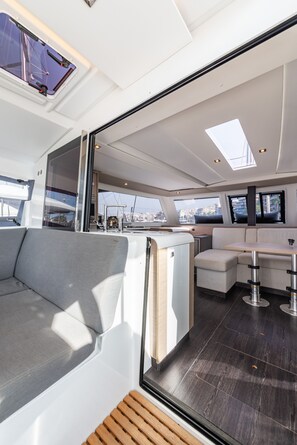 A modern yacht interior with a seating area, a bar, and large windows offering views of the city.