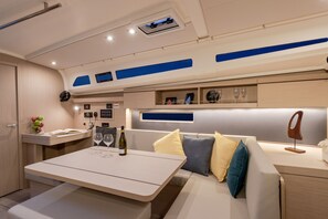 Ein modernes Interieur mit Essbereich, einer Couch mit Kissen, einem kleinen Tisch und einer Wandregal mit Dekoration.