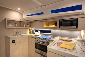A compact kitchen with a stove, oven, microwave, and a sink.