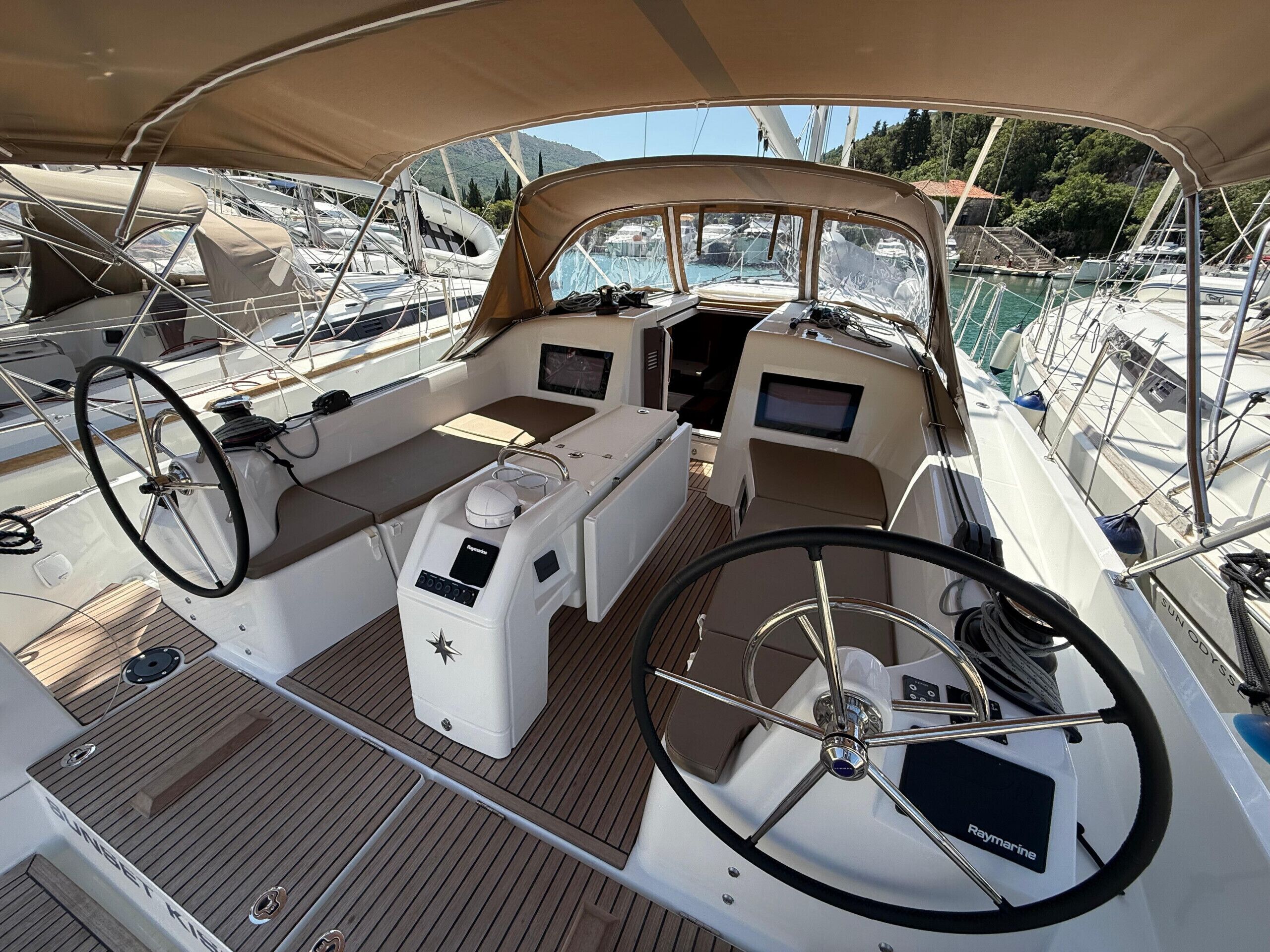 Cubierta de barco con timón, panel de control y zona de estar.