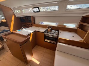 A compact galley with a sink, stove, and storage cabinets. - Dubrovnik Delight: A Sun-Kissed Sailing Experience (Komolac)