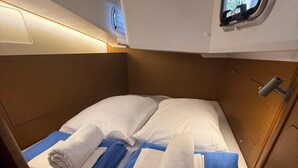 Ein kleines Blockhaus mit einem Einzelbett, einem kleinen Fenster und einem hölzernen Kopfteil.