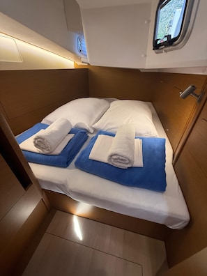Una cabaña pequeña con una cama individual, una ventana pequeña y un cabecero de madera.