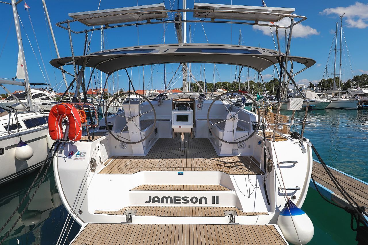 Un port de plaisance où est amarré un bateau appelé « JAMESON II », qui se distingue par son pont en bois, son gouvernail et ses gilets de sauvetage.