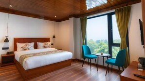 A hotel room with a wooden ceiling, a large bed with white linens, two chairs, a small table, and a view of greenery through the window. - Mystique Valley by Trekocity  (Lachung)