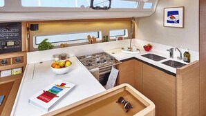A compact galley with a stove, sink, and storage cabinets. - Sun-Kissed Sailing Adventure in Northern Croatia (Punat)