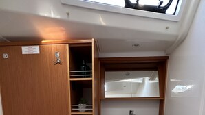 Un bagno piccolo ma funzionale, con il water bianco, un lavandino e uno specchio sopra. Si nota un armadietto in legno con uno scaffale e una piccola pianta.