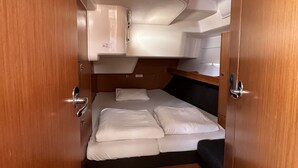Un intérieur compact comprenant un lit superposé, une petite kitchenette et une porte dotée d’une poignée.