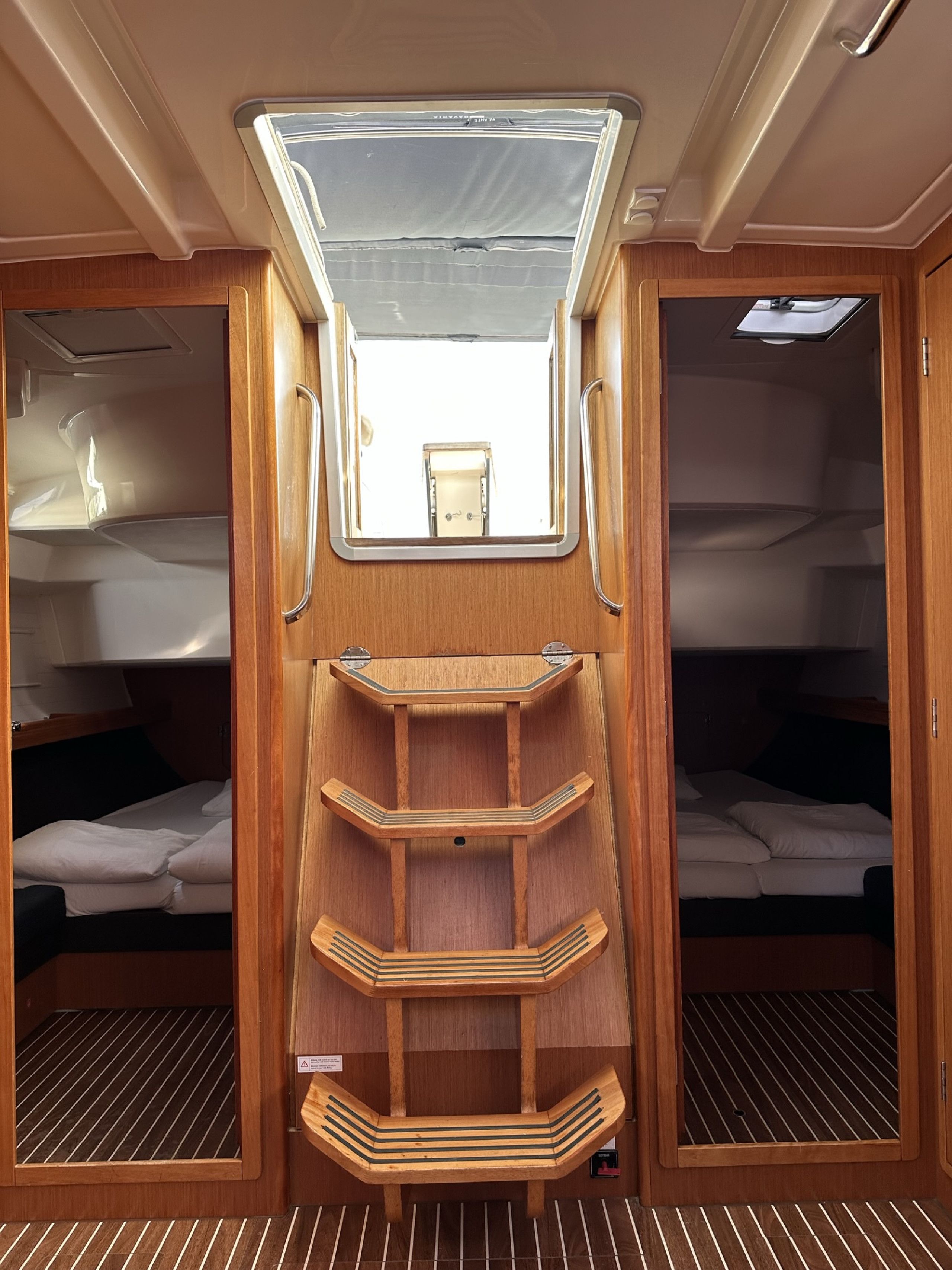 Un intérieur compact avec une bibliothèque centrale en bois, deux lits dotés de têtes de lit et une lucarne au-dessus.