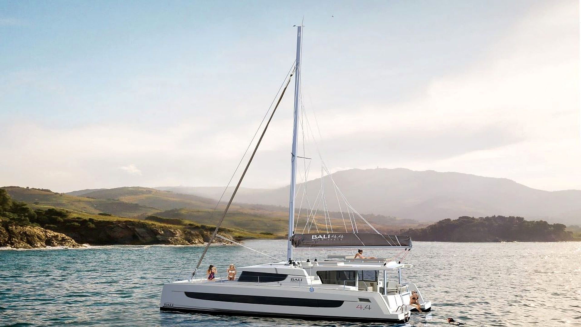 A sailboat named 'BALI 44' on calm waters with a mountainous landscape in the background.
