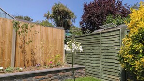Een tuin met een houten omheining, een stenen muur en verschillende planten.