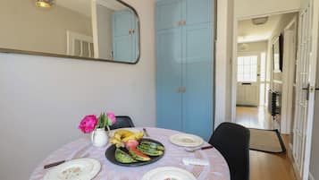 A dining area with a round table set for four, a blue wardrobe, and a mirror on the wall.