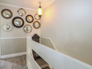 A staircase with a white railing, a patterned rug, and multiple wall-mounted mirrors. - The Dacha (Winchester)