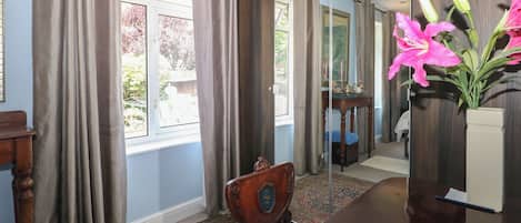 Una habitación con un espejo grande, un escritorio de madera, una silla, un tapete y una ventana con cortinas.
