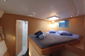 A bedroom with a bed, a shower, a painting, and a light fixture. - Sun-Kissed Sailing Adventure in Islas Sarónicas (Alimos)