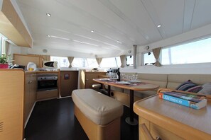 A compact galley with a stove, oven, and a dining area with a bench and table. - Sun-Kissed Sailing Adventure in Islas Sarónicas (Alimos)