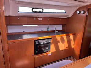 A compact kitchen with a built-in oven, a window above the sink, and a small countertop. - Sun-Kissed Sailing Adventure in Northern Croatia (Punat)