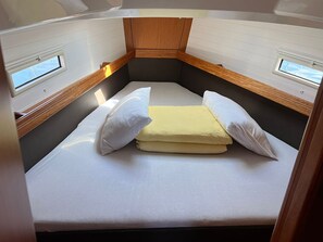 A compact RV interior with a bed, two windows, and a wooden ceiling. - Sun-Kissed Sailing Adventure in Northern Croatia (Punat)