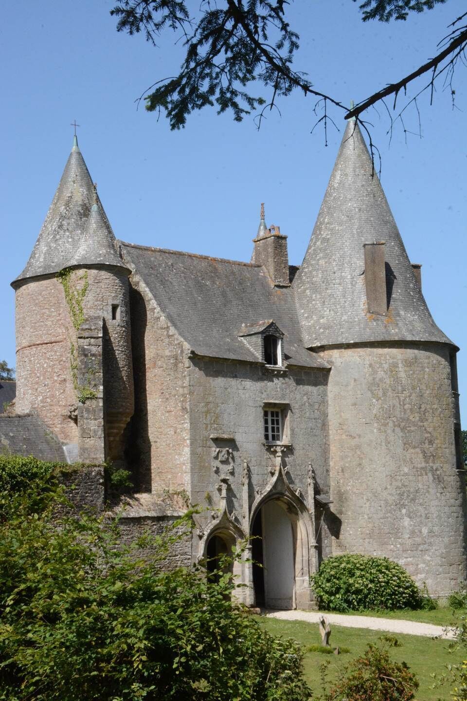 Eine historische Burg mit zwei markanten Türmen, einem zentralen Eingang und einem umgebenden Garten.