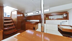 Eine schmale Kombüse mit einem zentralen Tisch, Holzschränken und einem kleinen Fenster.
