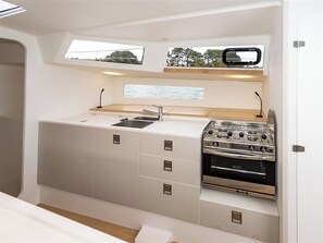 A compact kitchen with a sink, stove, and storage cabinets.