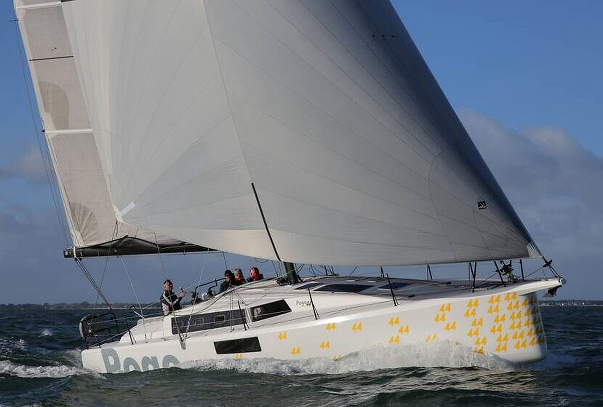 A sailboat with a white hull and yellow markings, sailing on the water.