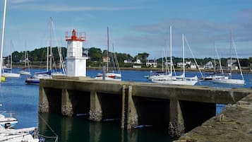 Un port avec des bateaux, un phare et des maisons en arrière-plan.