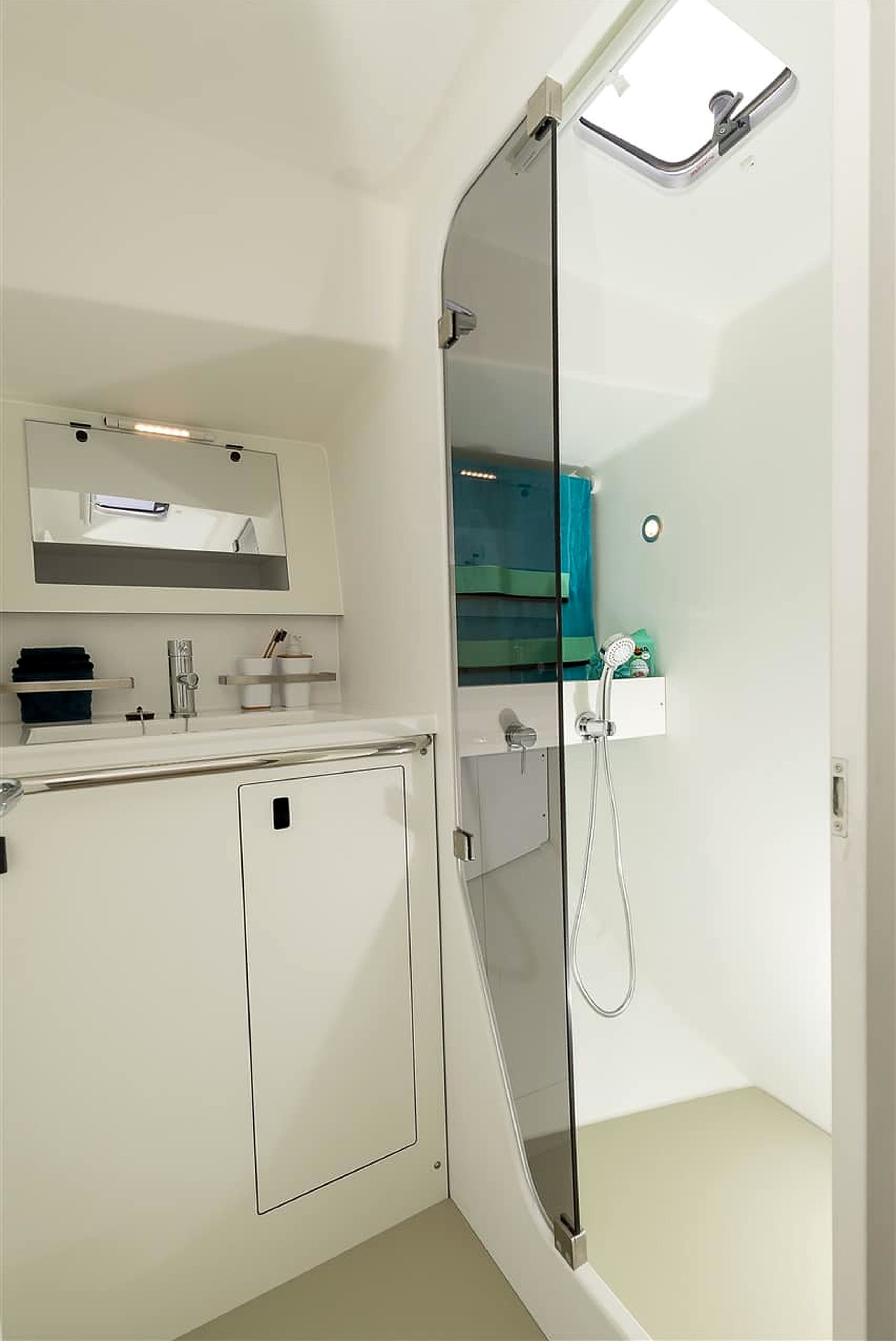 A modern bathroom with a glass shower enclosure, a white sink, and a mirror above the countertop.