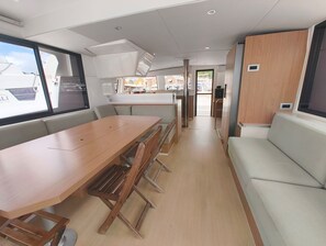 A boat interior with a dining area, a sofa, and a kitchen.