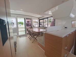 A modern kitchen with a dining area, wooden cabinets, and a large window. - Caribbean Dream: Sun-Kissed Sailing Adventure from Guadalupe, Grande-Terre (Pointe-à-Pitre)