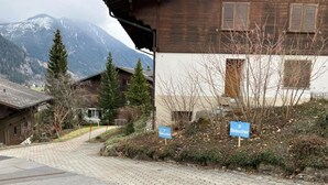 Ein Gebäude mit Holzfassade, befestigtem Eingangsbereich und Schildern, die auf einen Parkplatz hinweisen.