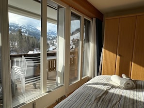 Une chambre d’hôtel avec un lit, une fenêtre donnant sur un paysage enneigé et une tête de lit en bois.
