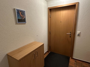 A hallway with a wooden door, a small cabinet, and a framed picture on the wall. - Hübeli (Streit) Appartement/Fewo, Dusche und Bad, WC 6-Bettwohnung by Interhome (Zweisimmen)