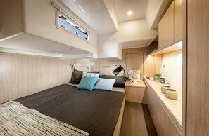 A compact, well-lit cabin with a bed, bedside table, and a small workspace. - Sun-Kissed Sailing Adventure in Istria, Croatia (Pula)